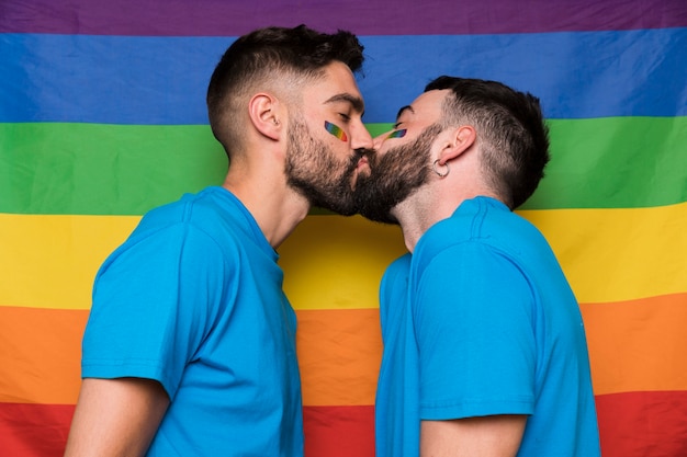 Pareja de homosexuales de hombres besándose en una bandera de arcoiris LGBT