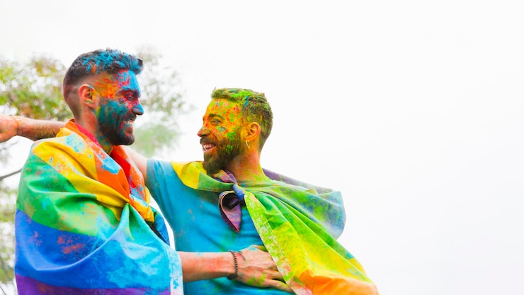 Foto gratuito pareja de homosexuales con rostros pintados riendo y abrazándose.