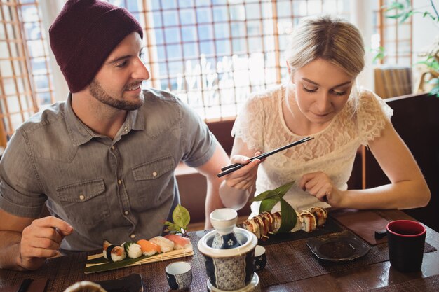 Pareja interactuando entre sí mientras toma sushi