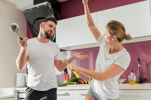 Pareja en el interior bailando en la cocina tiro medio