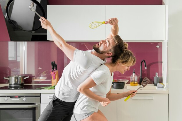 Pareja en el interior cantando en la cocina sentado en la vista lateral