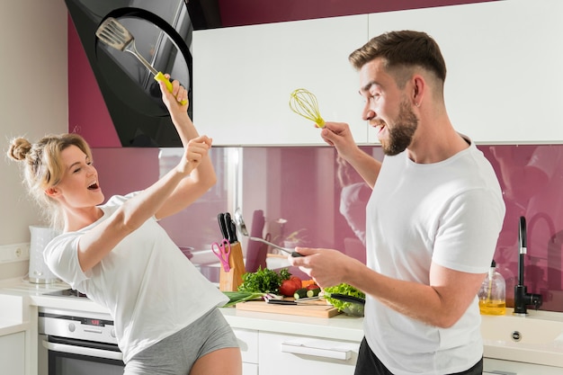 Pareja en el interior jugando en la cocina con objetos