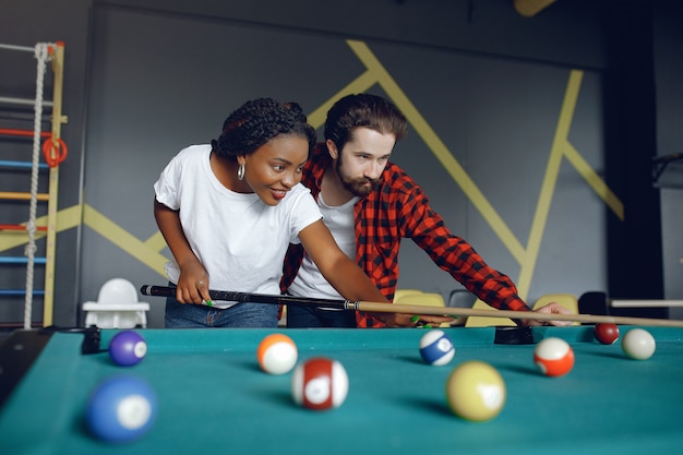 Pareja internacional jugando billar en un club