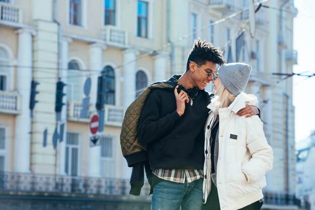 Pareja interracial amorosa de pie delante del edificio