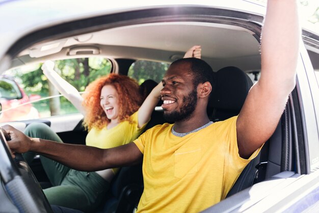 Pareja interracial divirtiéndose en un viaje en coche