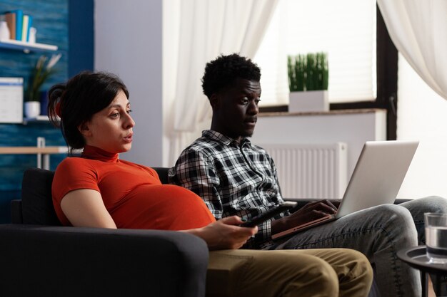 Pareja interracial esperando un hijo y usando tecnología