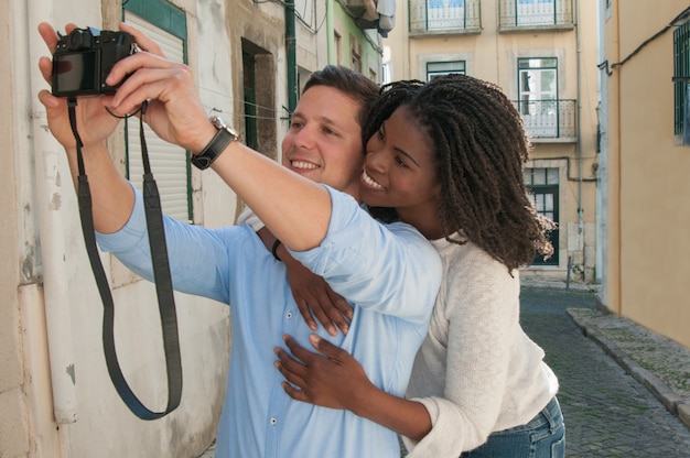 Pareja interracial feliz tomando foto selfie en la calle