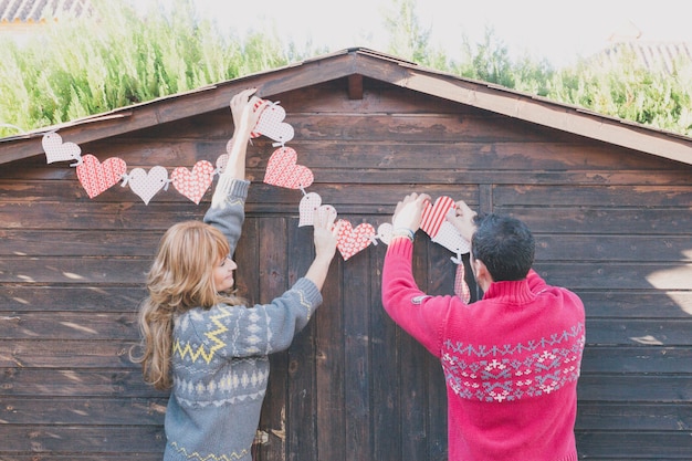 Pareja irreconocible decorando la casa con corazones de papel