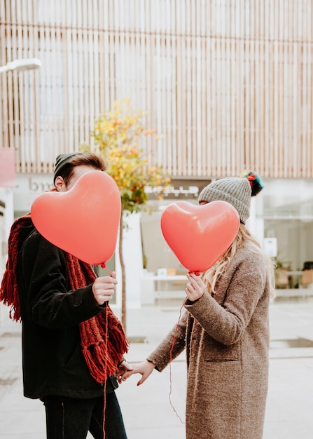 Pareja irreconocible con globos en forma de corazón