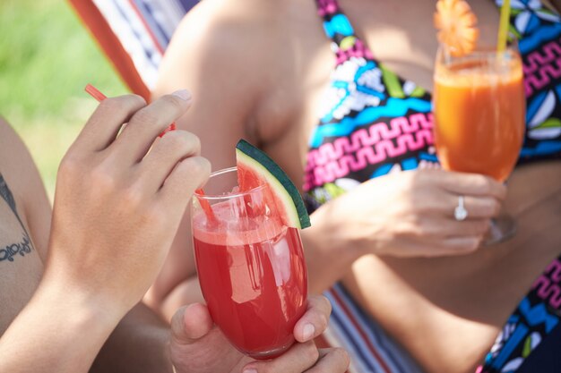 Pareja irreconocible en trajes de baño disfrutando de bebidas en lujoso resort