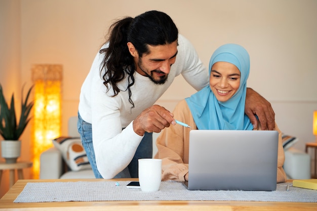 Foto gratuita pareja islámica sonriente de tiro medio con computadora portátil