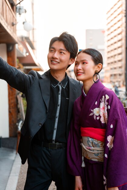 Pareja japonesa celebra el día de la mayoría de edad al aire libre tomándose una selfie