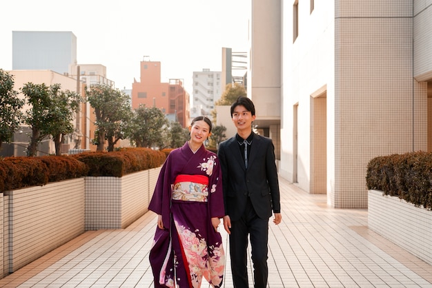 Foto gratuita pareja japonesa celebrando el día de la mayoría de edad y posando al aire libre en la ciudad