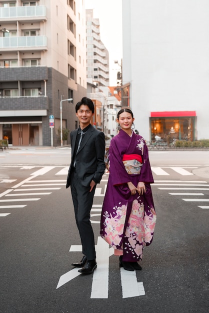 Pareja japonesa celebrando el día de la mayoría de edad y posando al aire libre en la ciudad