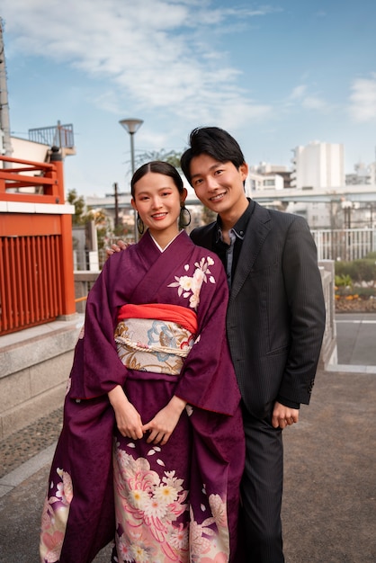 Foto gratuita pareja japonesa posando al aire libre y celebrando el día de la mayoría de edad