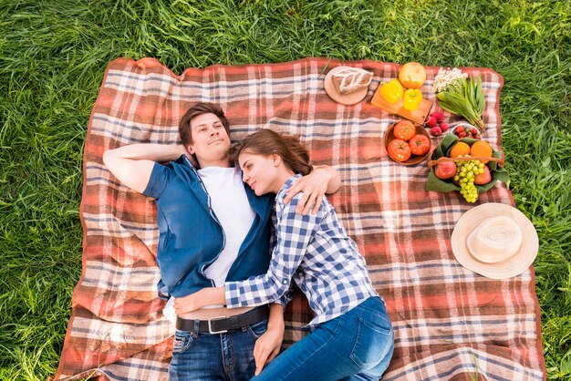 Pareja joven abrazando en manta durante picnic