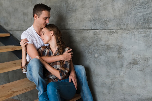 Foto gratuita pareja joven abrazando en pasos en casa