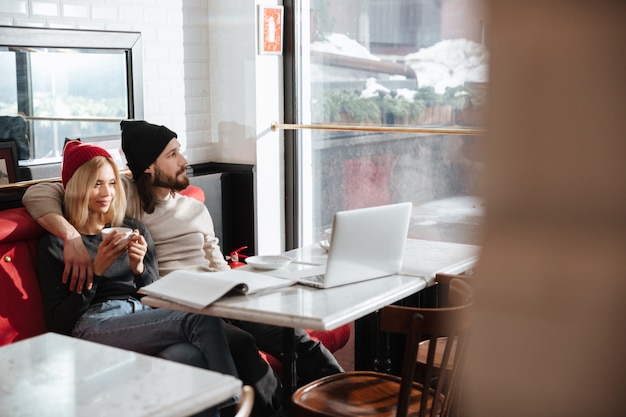 Pareja joven abrazando y sentado en la cafetería