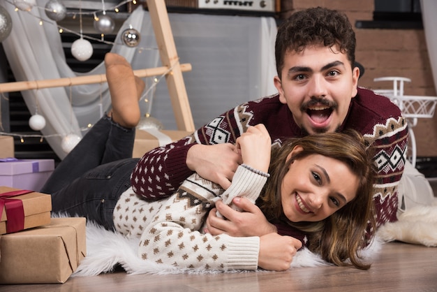 Pareja joven acostada en el suelo en el interior de Navidad.