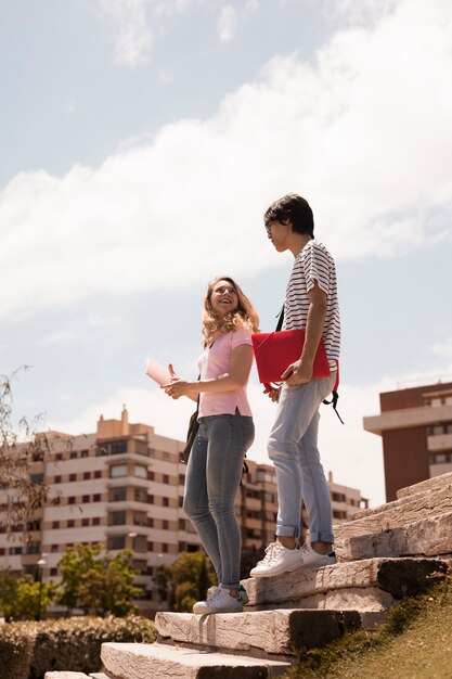 Pareja joven adolescente en las escaleras contra el paisaje urbano