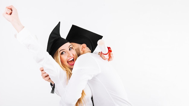 Foto gratuita pareja joven alegre celebrando diplomas