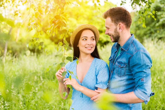 Pareja joven alegre sonriendo el uno al otro con amor en la naturaleza