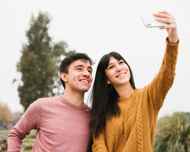 Pareja joven alegre tomando selfie con smartphone