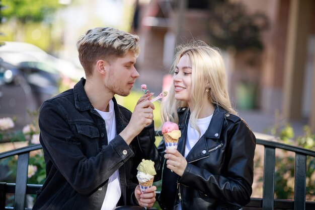 Una pareja joven alimentándose mutuamente con helado en el parque Foto de alta calidad