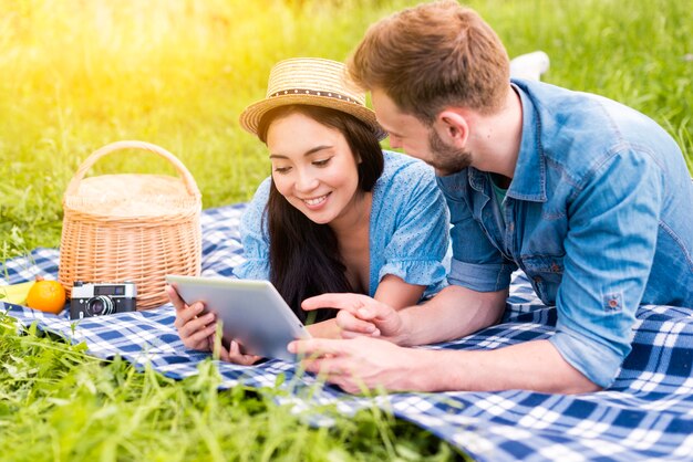 Pareja joven amante de la web que practica surf usando la tableta en campo