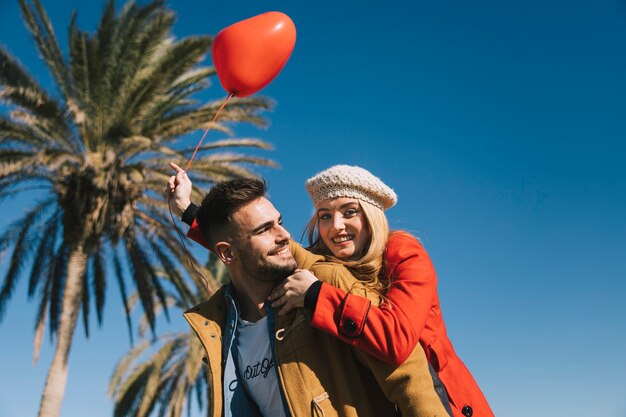 Pareja joven amorosa con globo en la costa