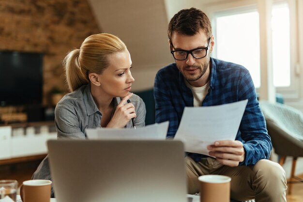 Pareja joven analizando su presupuesto mientras revisa las finanzas del hogar