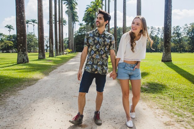 Pareja joven andando en camino de palmeras