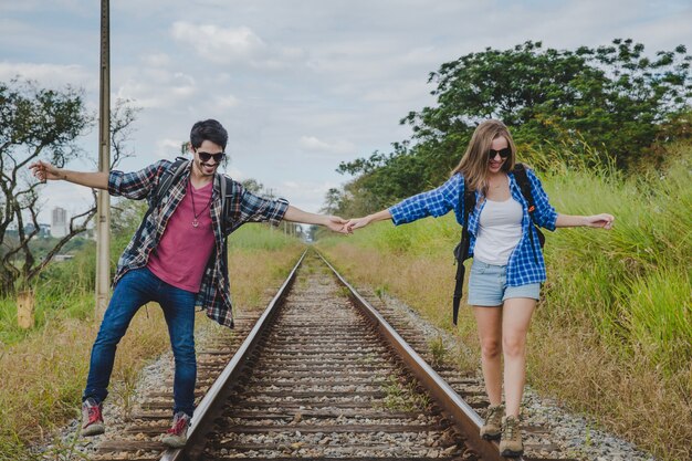 Pareja joven andando en vías de tren tomándose las manos