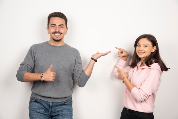 Pareja joven apuntando a sí mismos en blanco.