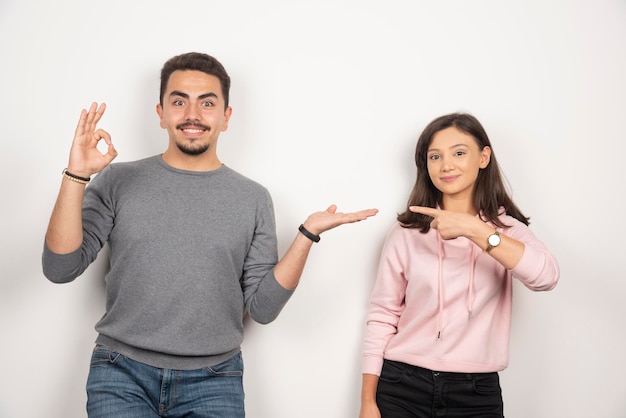 Pareja joven apuntando a sí mismos en blanco.