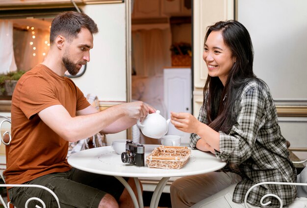 Pareja joven aventurero tomando una taza de té junto a la camioneta