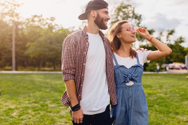 Pareja joven bastante hipster caminando en el parque, amigos divirtiéndose juntos, romance en la fecha, estilo de moda de verano, traje colorido hipster, hombre y mujer sonriendo abrazándose