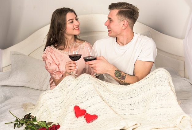 Foto gratuita pareja joven bebiendo vino en la cama