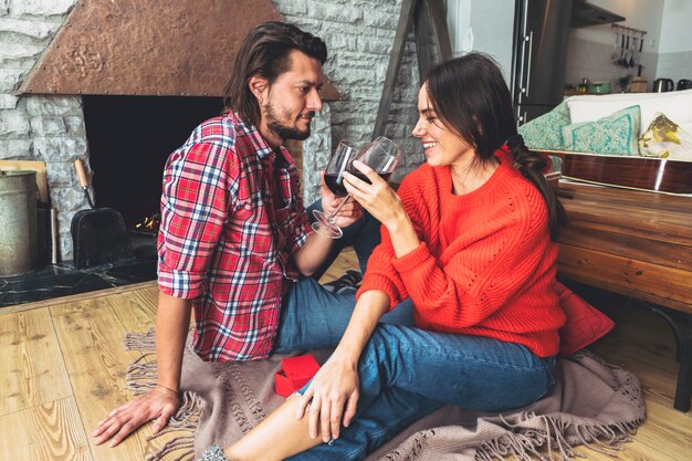 Pareja joven bebiendo vino en el piso