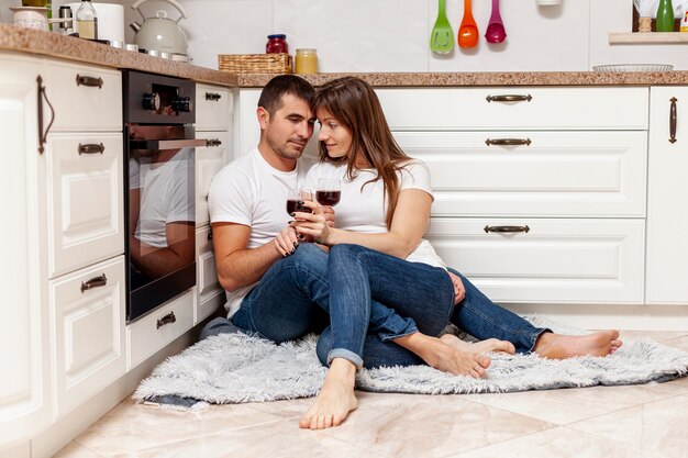 Pareja joven bebiendo vino en el piso