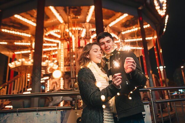 Pareja joven besándose y abrazándose al aire libre en la calle de noche en Navidad