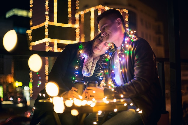 Pareja joven besándose y abrazándose al aire libre en la calle de noche en Navidad