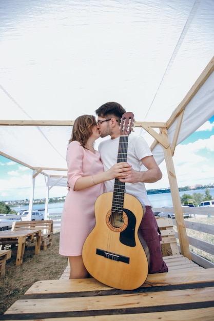 Pareja joven besándose y sujetando una guitarra