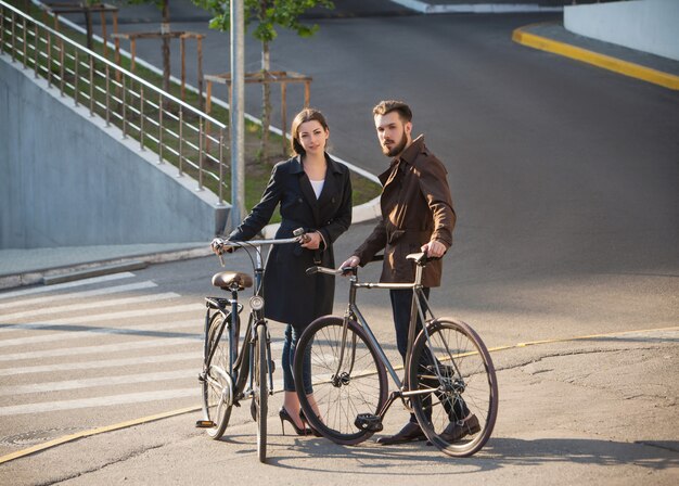 Pareja joven con una bicicleta frente a la ciudad