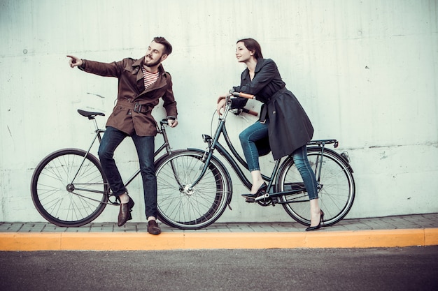 Pareja joven con una bicicleta frente a la ciudad