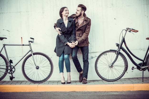 Pareja joven con una bicicleta frente a la ciudad