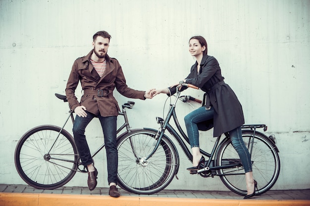 Pareja joven con una bicicleta frente a la ciudad