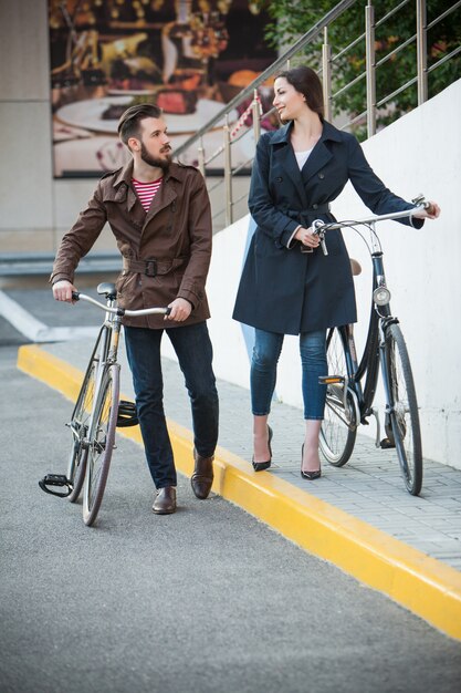 Pareja joven con una bicicleta frente a la ciudad