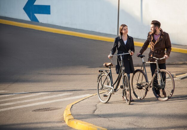 Pareja joven en bicicleta frente a la ciudad