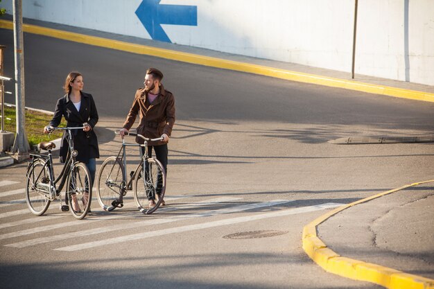 Pareja joven con una bicicleta frente a la ciudad